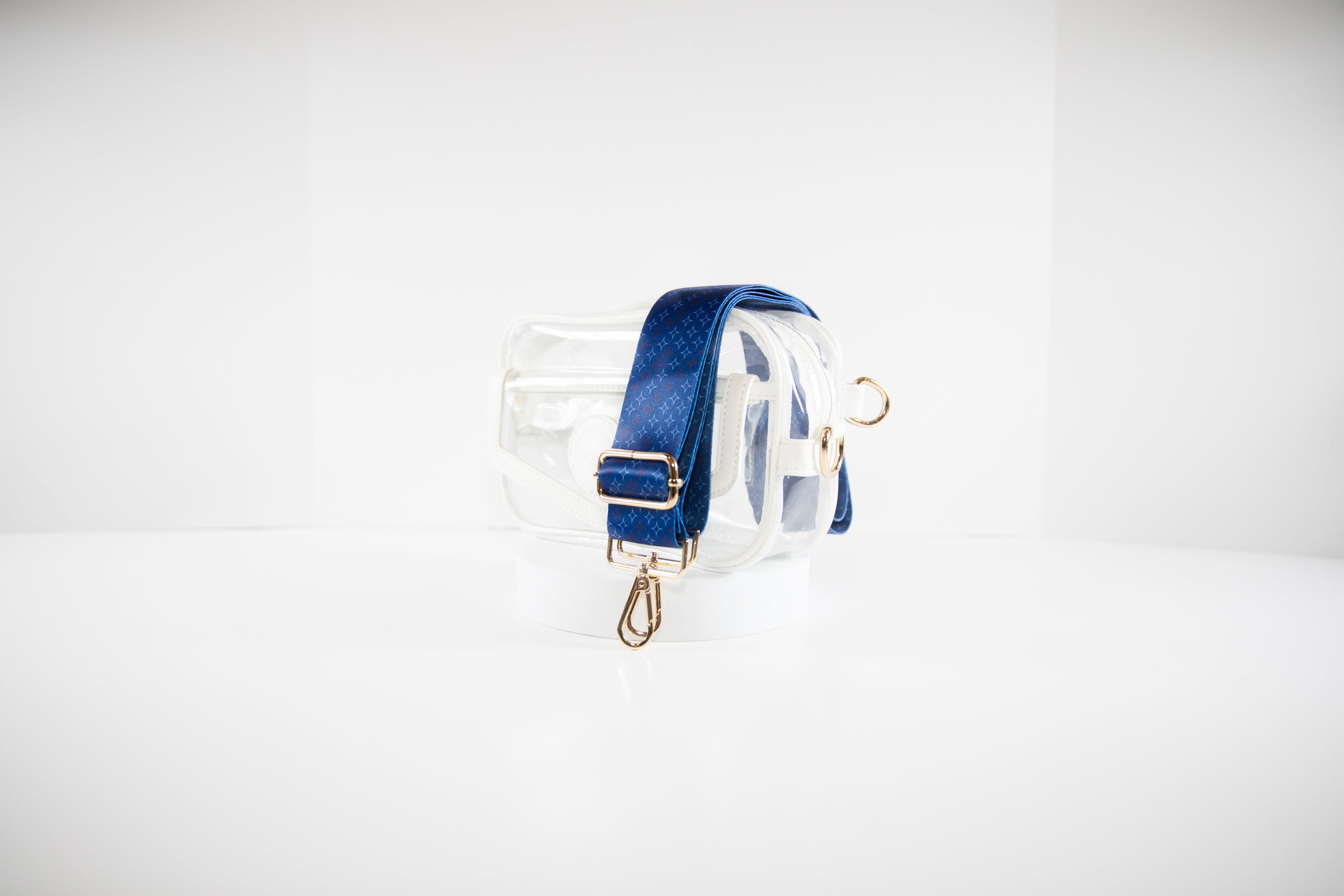 Clear stadium bag shown in white leather trim with a crossbody strap in red, white and blue team colors of the Chicago Cubs.