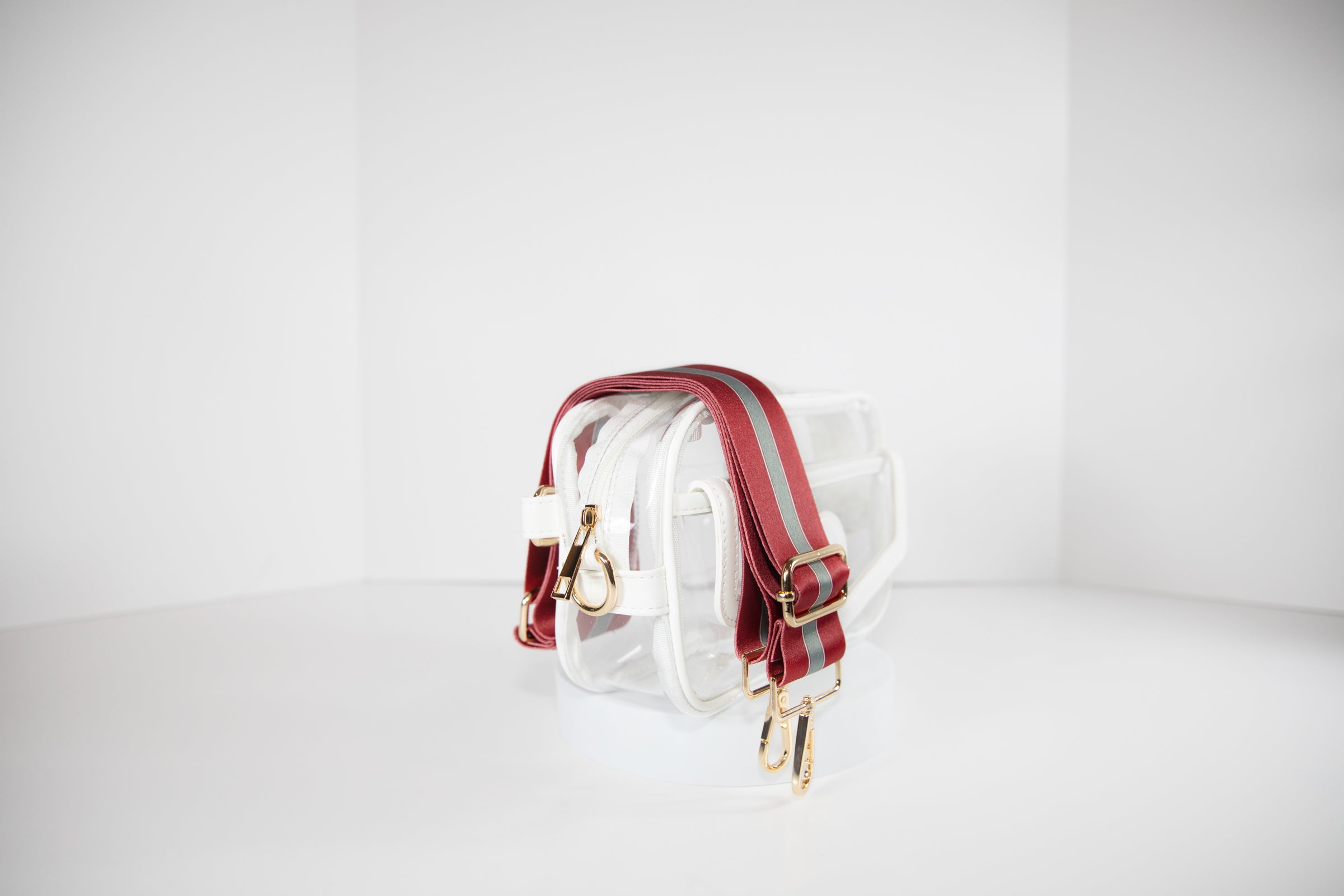 Clear stadium bag with white leather trim, side facing, with a crossbody strap in team colors of Alabama Crimson Tide.